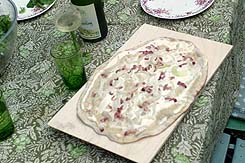 Fertiger Flammkuchen frisch aus dem Ofen mit Riesling.